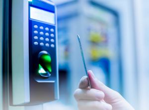 Close-up of an access control system with a biometric scanner and keypad, with a person holding a keycard near the reader.