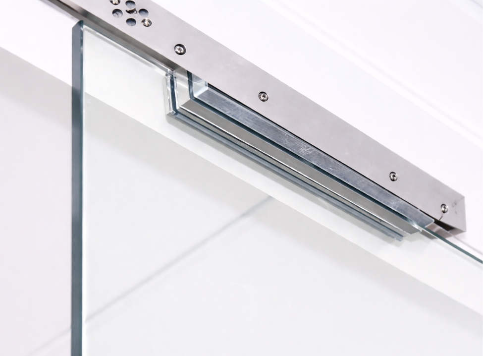 Electromagnetic door lock mounted on a frameless glass door, featuring a sleek brushed metal housing and secure magnetic plate, shown in a clean, bright installation with modern access control hardware.